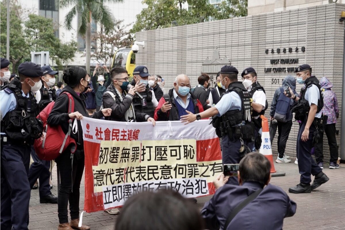 Tři členové Ligy sociálních demokratů uspořádali protest před soudem s HK 47 a požadovali propuštění politických vězňů. Byli obklíčeni početným kontingentem policistů a odvedeni do „demonstračního prostoru“ na opačné straně hongkongského magistrátního soudu v Západním Kowloonu 6. února 2023. (Adrian Yu / The Epoch Times)