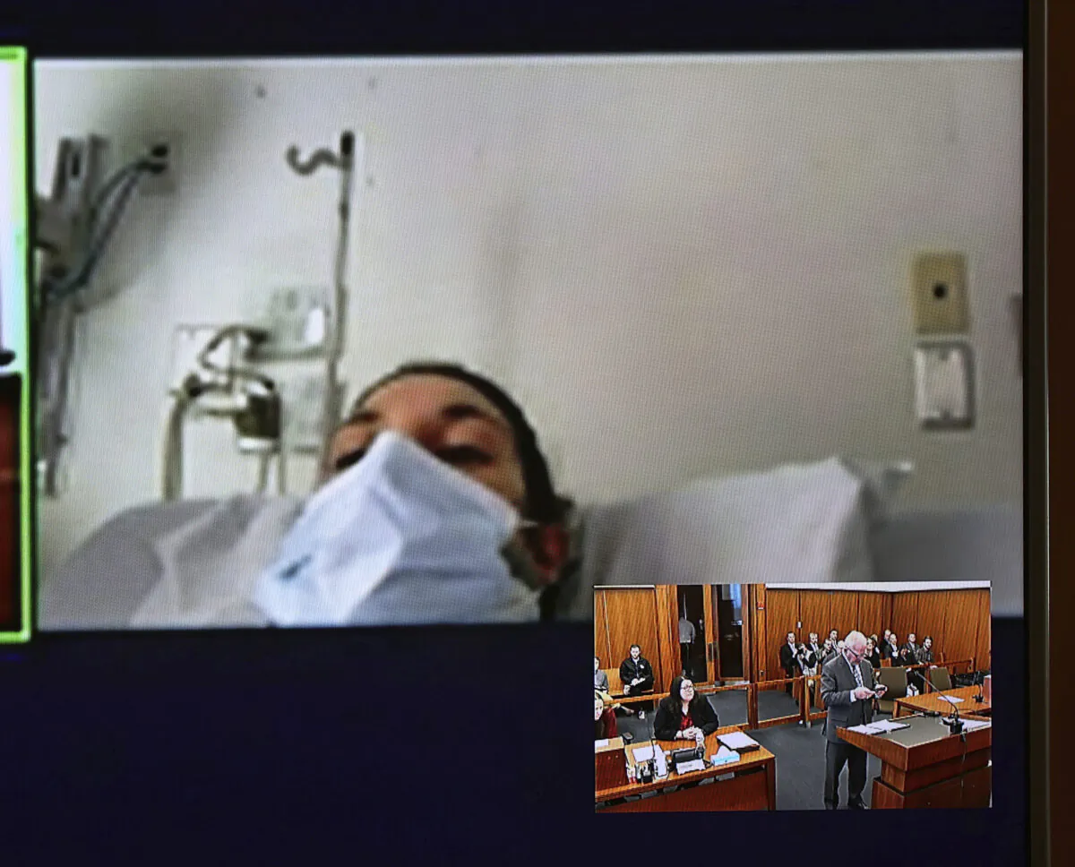 In this video screen image, Lindsay Clancy with a surgical mask over her face in a hospital appears during her arraignment on charges regarding her three children's deaths at Plymouth District Court in Plymouth, Mass. Tuesday, Feb. 7, 2023. (David Ryan/The Boston Globe via AP, Pool)