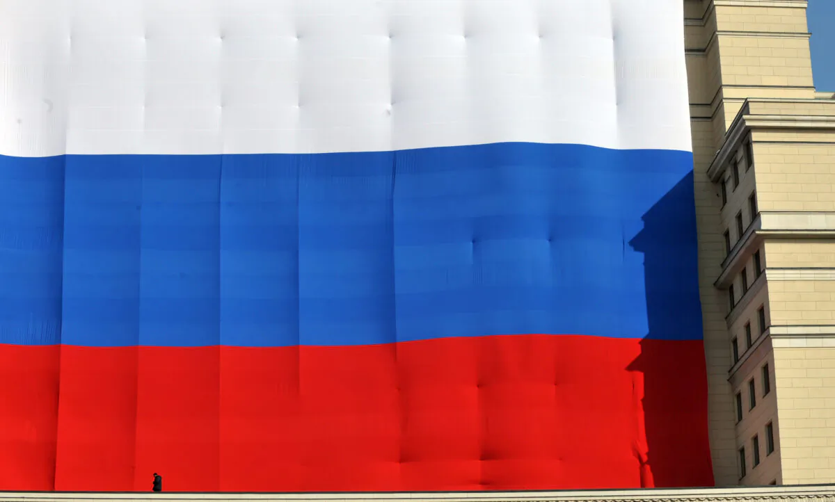 A man walks in front of a huge Russian flag hanging on the Moskva Hotel's facade at the central Manezhnaya Square just outside the Kremlin in Moscow on March 6, 2012. (Sergei Supinsky/AFP via Getty Images)
