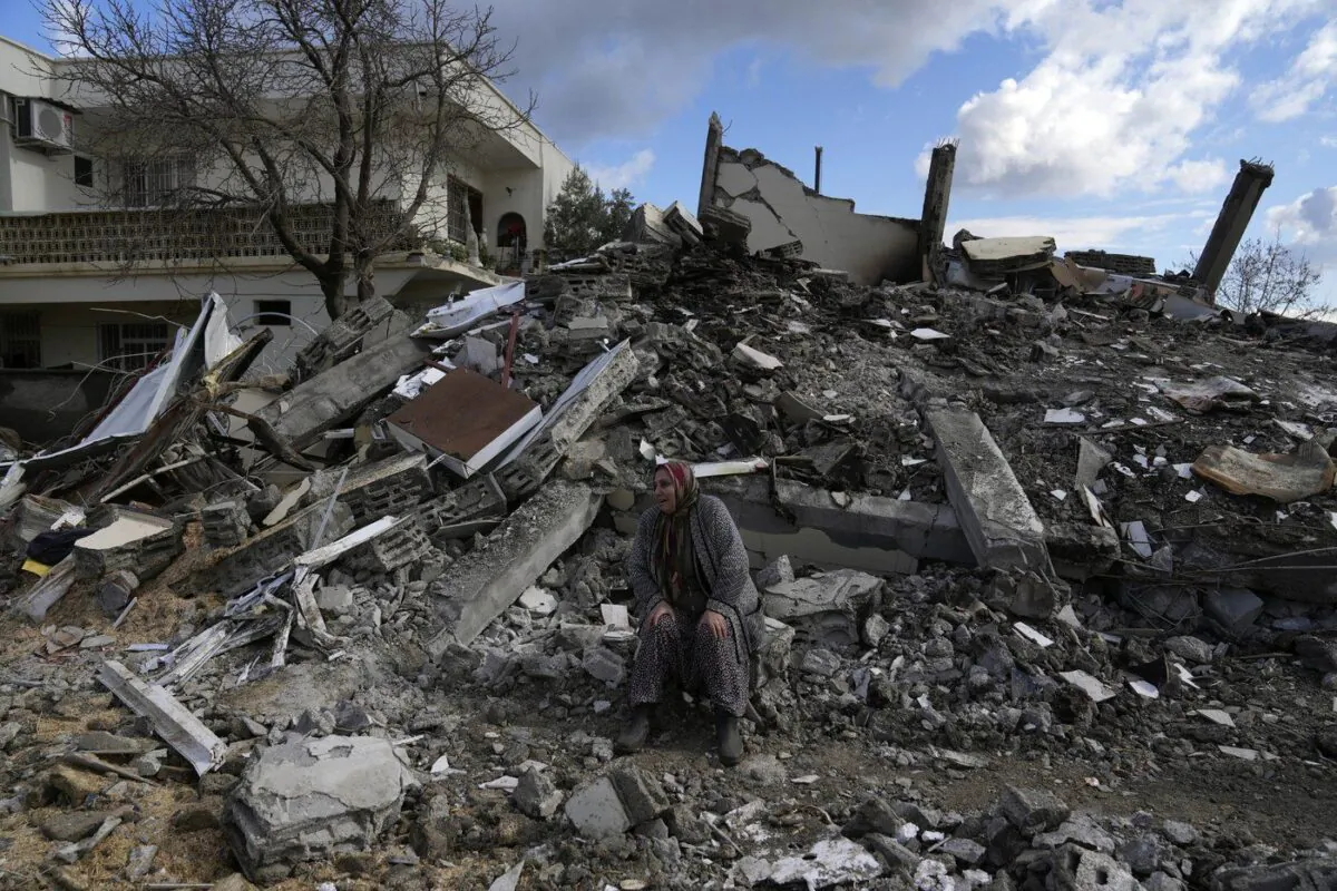 A woman sits on the rubble as emergency rescue teams search for people under the remains of destroyed buildings in Nurdagi town on the outskirts of Osmaniye city southern Turkey, Feb. 7, 2023. (The Canadian Press/AP/Khalil Hamra)
