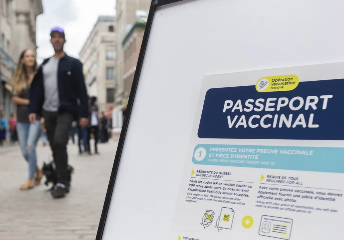 People walk by a sign outside a restaurant advising customers of the Quebec government’s COVID-19 vaccine passport in Montreal, Sept. 6, 2021. (The Canadian Press/Graham Hughes)