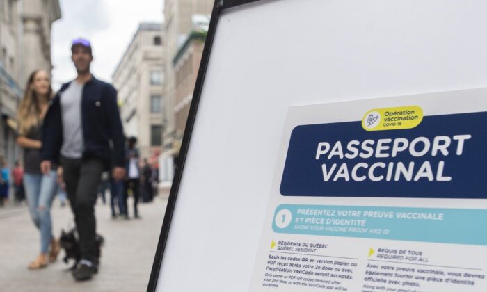 People walk by a sign outside a restaurant advising customers of the Quebec government’s COVID-19 vaccine passport in Montreal, Sept. 6, 2021. (The Canadian Press/Graham Hughes)
