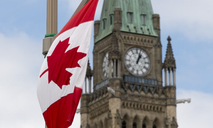A Canadian flag hangs from a lamp post along the road in front of the Parliament buildings ahead of Canada Day in Ottawa on June 30, 2020. (Adrian Wyld/The Canadian Press)