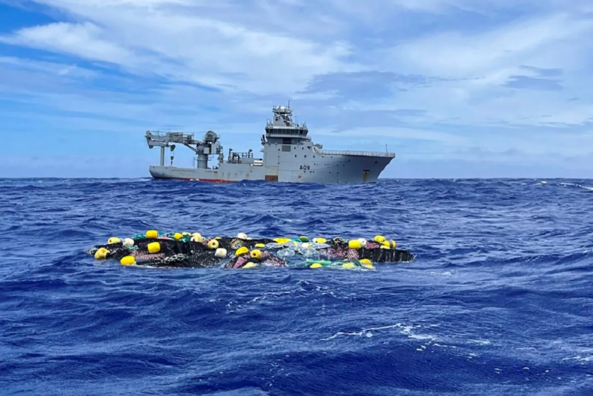 A shipment of cocaine floats on the surface of the Pacific Ocean with Royal New Zealand Navy vessel HMNZS Manawanui behind, in a file photo. (NZ Police via AP)