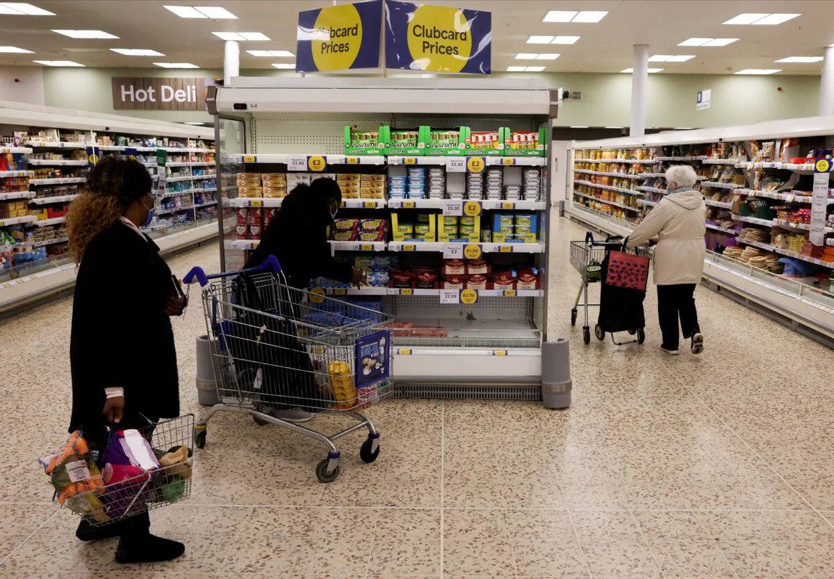 People shop next to the clubcard price branding inside a branch of a Tesco Extra Supermarket in London on Feb. 10, 2022. (Paul Childs/Reuters)