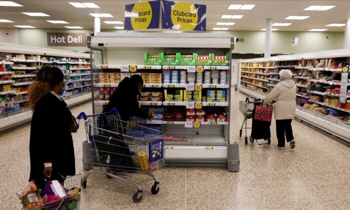 People shop next to the clubcard price branding inside a branch of a Tesco Extra Supermarket in London on Feb. 10, 2022. (Paul Childs/Reuters)