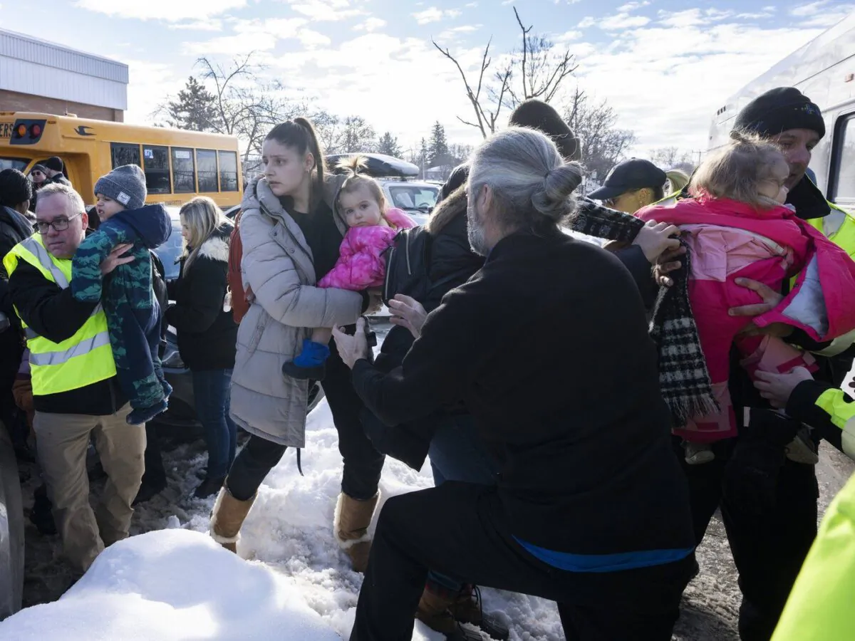 Parents and their children are loaded onto a warming bus as they wait for news after a bus crashed into a daycare centre in Laval, Que., on Feb. 8, 2023. (The Canadian Press/Ryan Remiorz)
