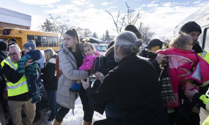 Parents and their children are loaded onto a warming bus as they wait for news after a bus crashed into a daycare centre in Laval, Que., on Feb. 8, 2023. (The Canadian Press/Ryan Remiorz)
