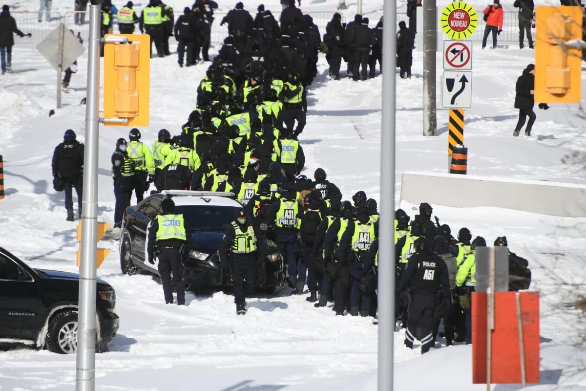 Police officers assemble on Colonel By Drive near the convoy trucks in Ottawa on Feb. 18, 2022. (The Canadian Press/Justin Tang)
