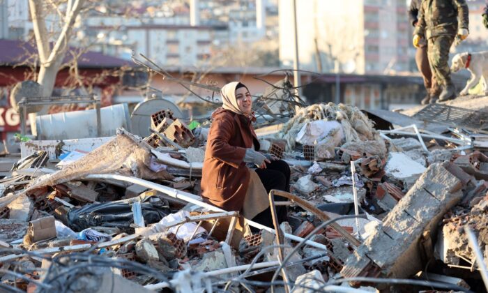 A woman sits on the rubble of a destroyed building in Kahramanmaras, southern Turkey, a day after a 7.8-magnitude earthquake struck the country's southeast, on Feb. 7, 2023. (Adem Altan/AFP via Getty Images)