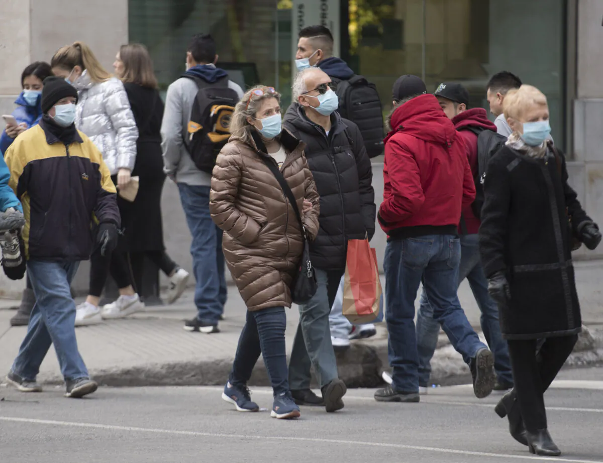 People wear face masks as they walk along a street in Montreal during the pandemic, on Nov. 29, 2020. (Graham Hughes/The Canadian Press)