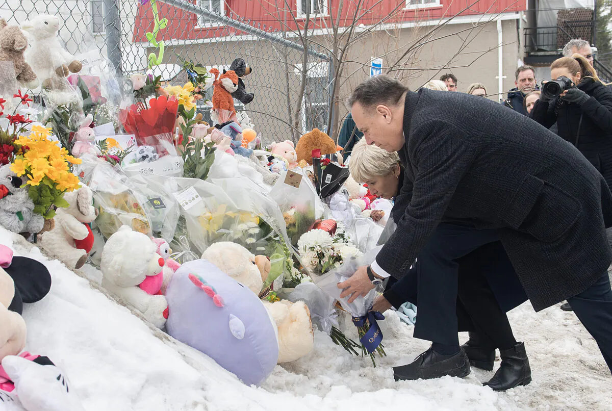 Quebec Premier Francois Legault lays flowers as he visits the site of a daycare centre in Laval, Quebec, Feb. 9, 2023, where a city bus crashed into the building killing two children. (Graham Hughes/The Canadian Press)