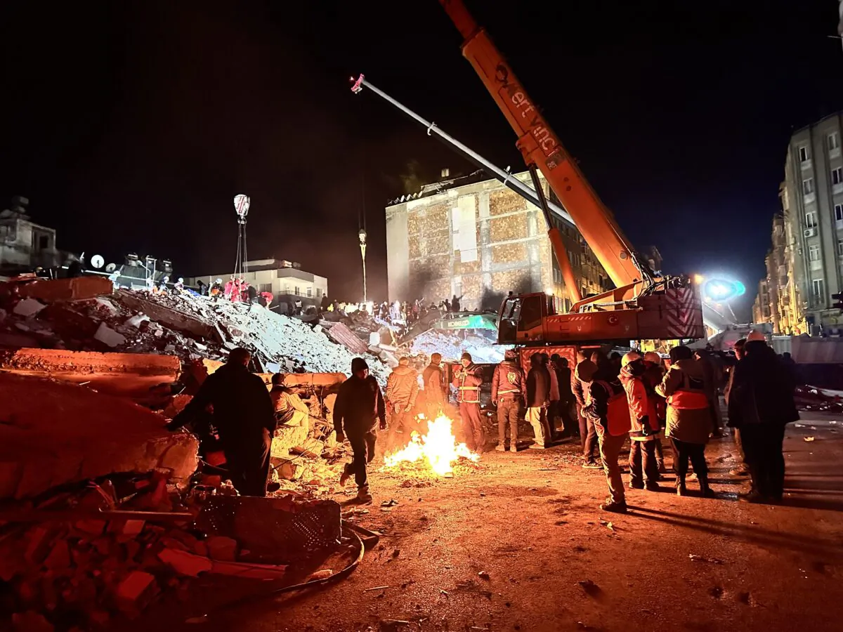 With nighttime temperatures below freezing, rescue workers stand near an open fire in Hatay’s Iskenderun province on Feb. 8, 2023. (Ercan Koc for The Epoch Times)