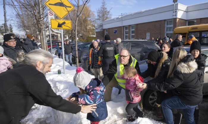 Parents and their children are loaded onto a warming bus as they wait for news after a bus crashed into a daycare centre in Laval, Que., on Feb. 8, 2023. (The Canadian Press/Ryan Remiorz
Ryan Remiorz)