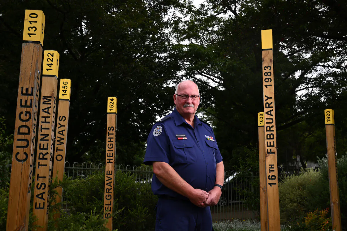 Former Cockatoo Fire Brigade Captain Graham Simpson poses for a photo with the Ash Wednesday Memorial at the Ash Wednesday Bushfire Education Centre, in Melbourne, Feb. 7, 2023. (AAP Image/Joel Carrett)