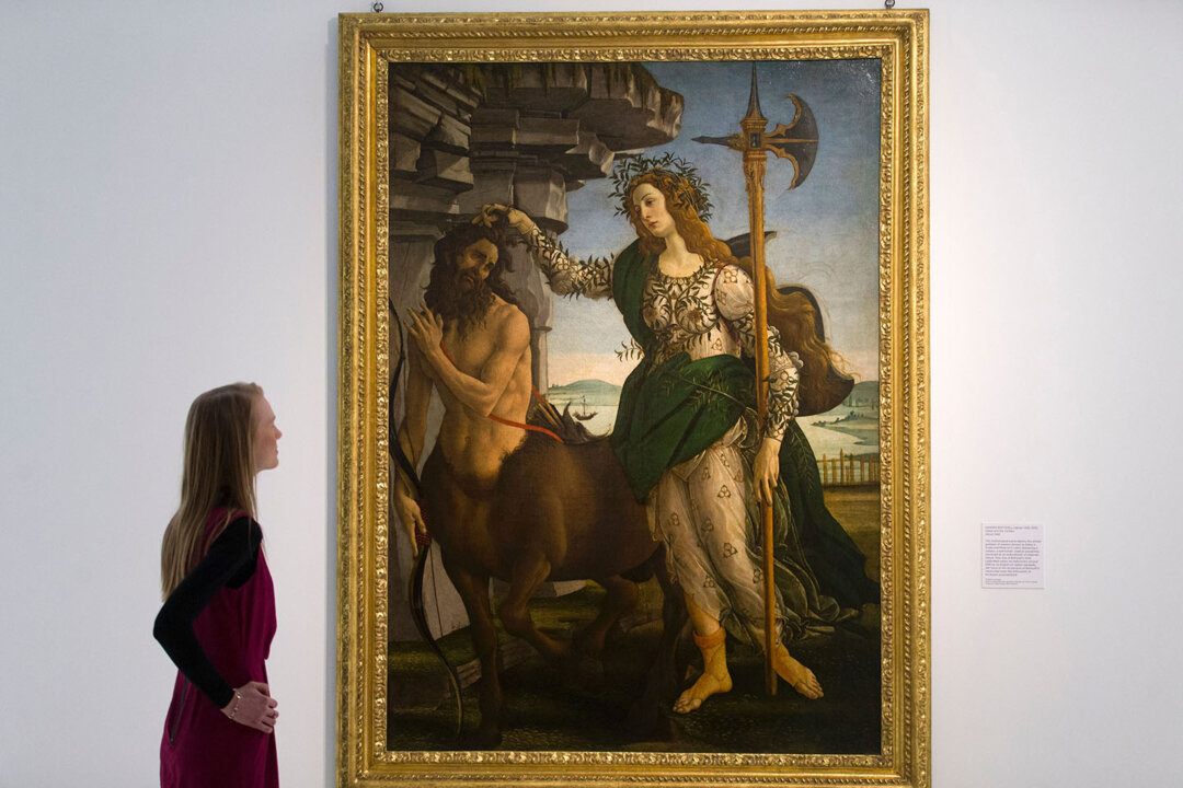 An employee poses for a photograph alongside "Pallas and the Centaur," circa 1482, by Italian artist Sandro Botticelli. (Justin Tallis/AFP/Getty Images)