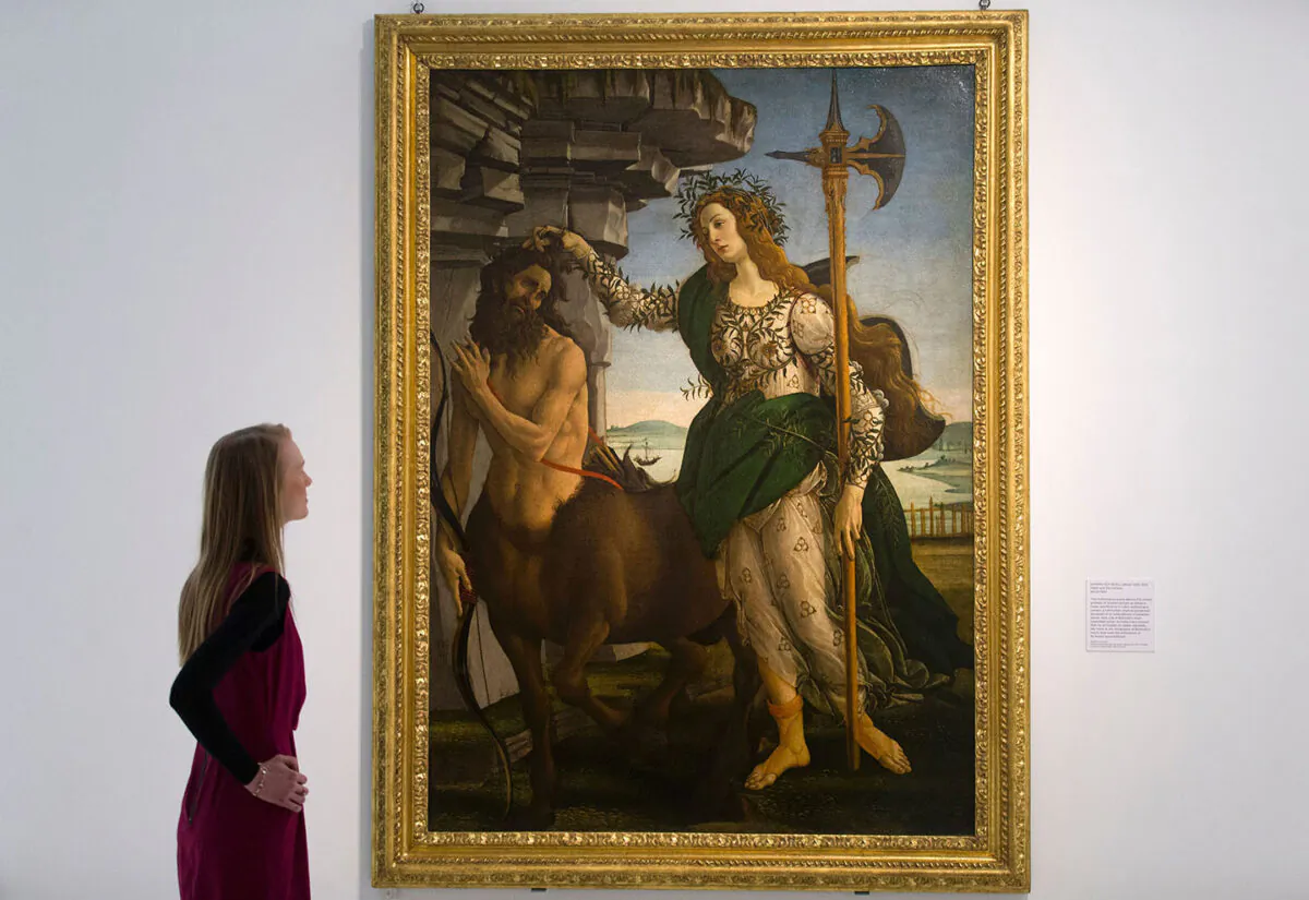 An employee poses for a photograph alongside "Pallas and the Centaur," circa 1482, by Italian artist Sandro Botticelli. (Justin Tallis/AFP/Getty Images)