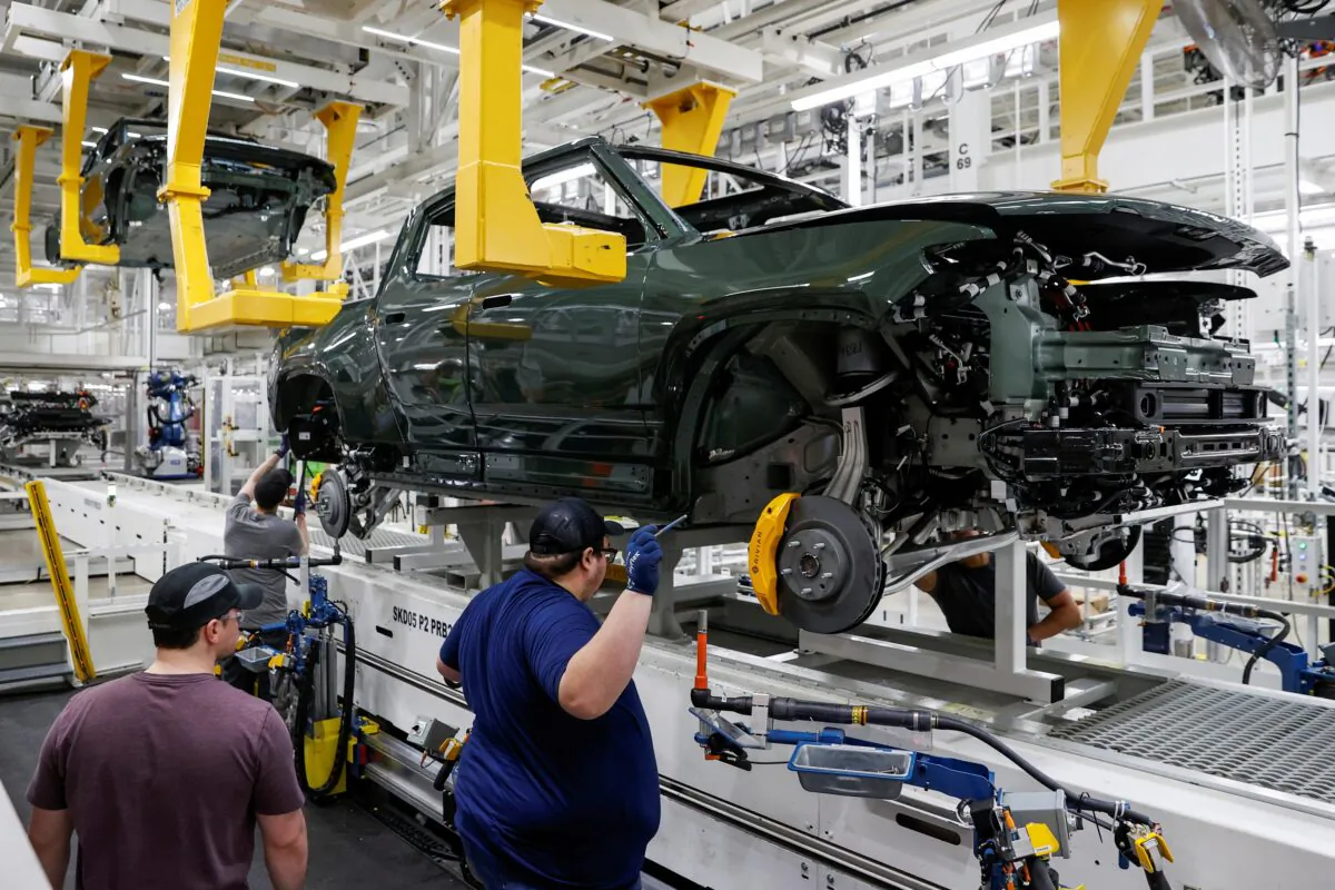 Employees works on an assembly line at startup Rivian Automotive's electric vehicle factory in Normal, Ill., on April 11, 2022. (Kamil Krzaczynski/Reuters)