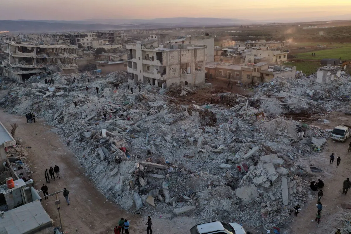 People walk past collapsed buildings following a devastating earthquake in the town of Jinderis, Aleppo Province, Syria, on Feb. 9, 2023. (Ghaith Alsayed/AP Photo)