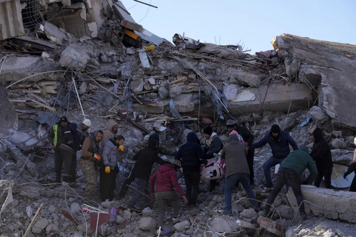 People carry a dead body from a collapsed building in Kahramanmaras, southern Turkey on Feb. 8, 2023. (The Associated Press/Hussein Malla)