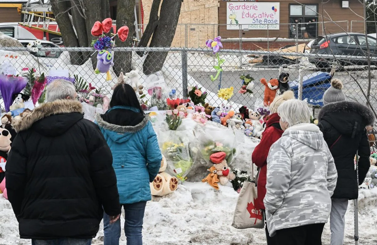 People stand next to a memorial at the site of a daycare centre in Laval, Que, Feb. 9, 2023, where a bus crashed into the building killing two children. (The Canadian Press/Graham Hughes)