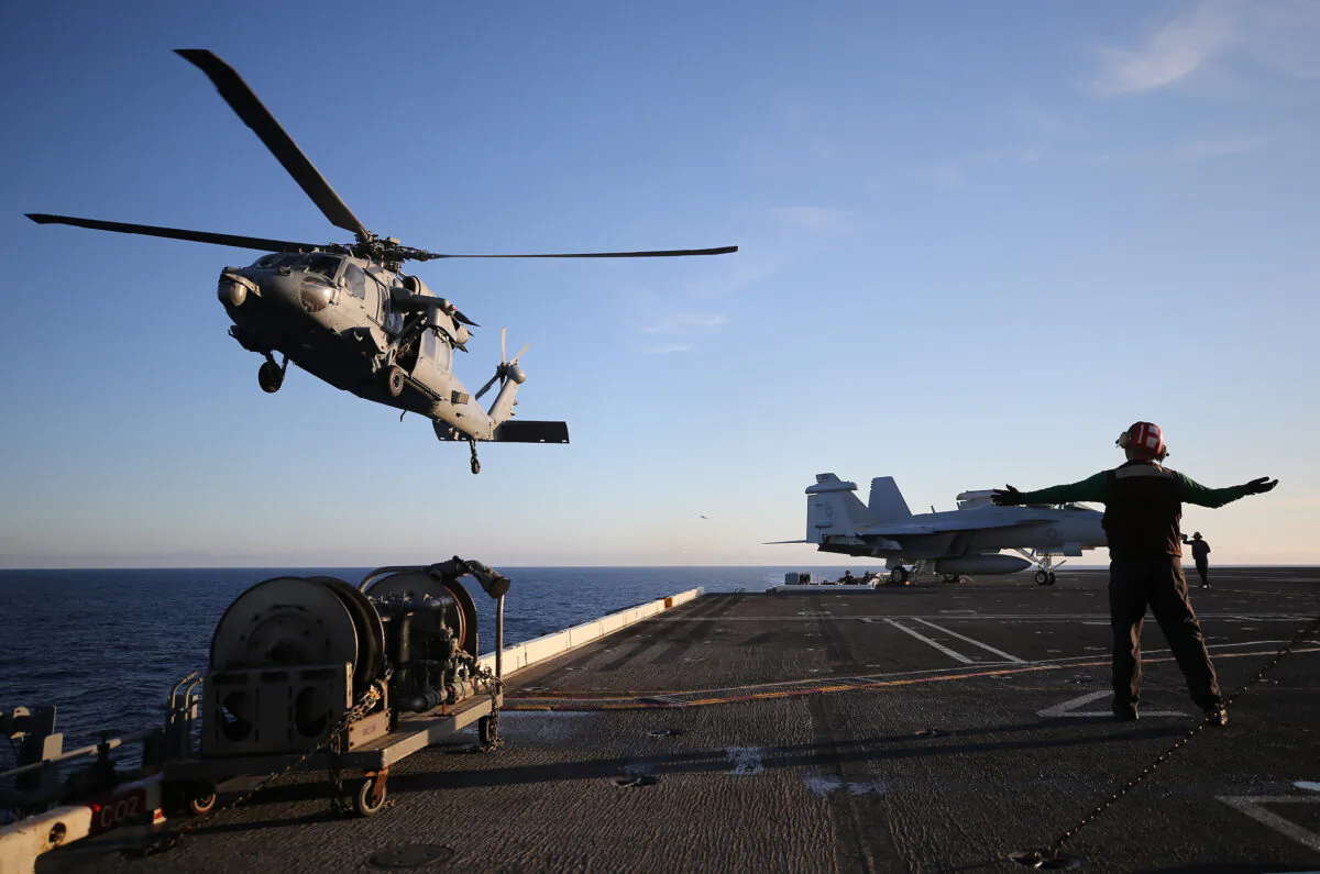 A U.S. Navy helicopter descends to land on the flight deck of the USS Nimitz (CVN 68) aircraft carrier while at sea off the coast of Baja California, Mexico, on Jan. 18, 2020. (Mario Tama/Getty Images)