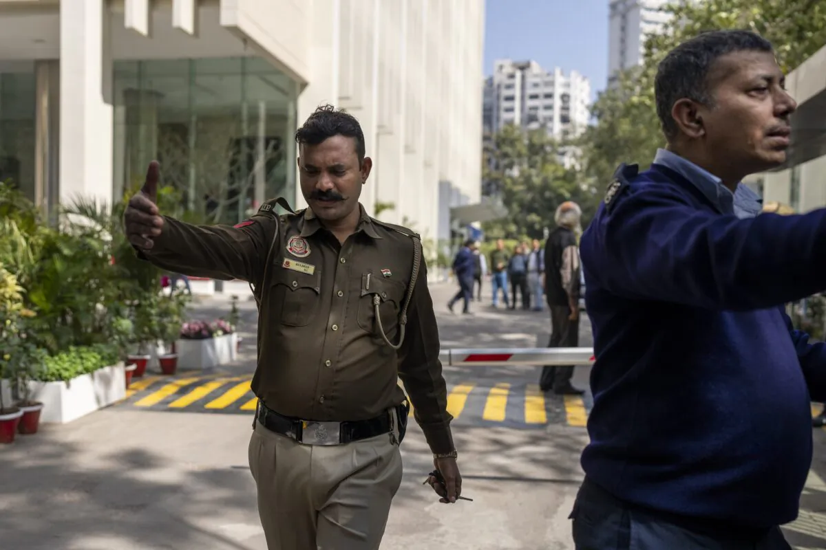 A police officer and a private security guard ask journalists to leave from the gate of a building housing BBC office in New Delhi on Feb. 14, 2023. (Altaf Qadri/AP Photo)