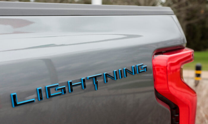 The Lightning logo on the side of an all-new Ford F-150 Lightning electric pickup truck outside the Ford Motor World Headquarters in Dearborn, Mich., on April 26, 2022. (Rebecca Cook/Reuters) 