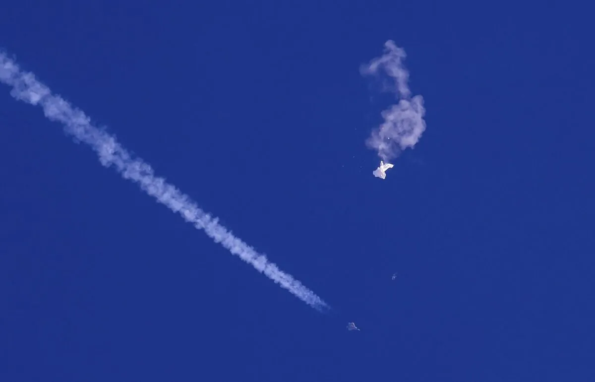 The remnants of a large balloon drift above the Atlantic Ocean, just off the coast of South Carolina, with a fighter jet and its contrail seen below it on Feb. 4, 2023. (The Canadian Press/AP-Chad Fish)