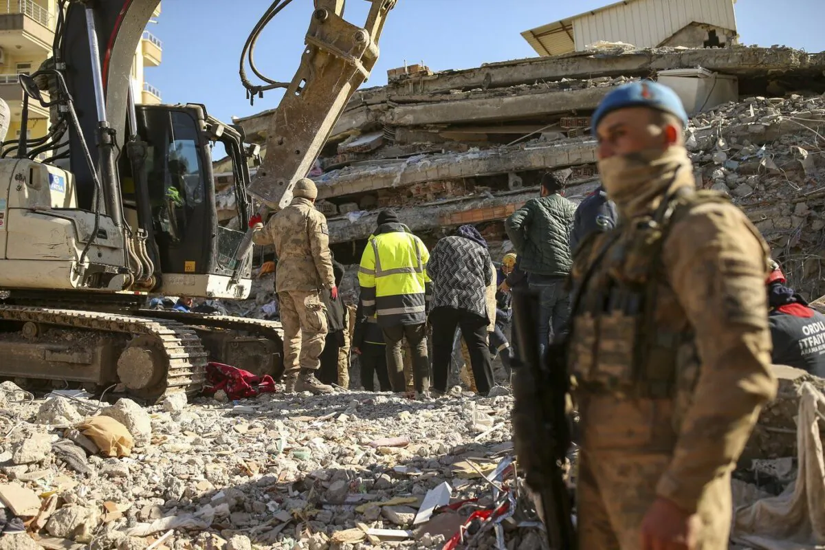 Rescue workers stand on a collapsed building in Adiyaman, southern Turkey, Feb. 13, 2023. (The Canadian Press/AP-Emrah Gurel)