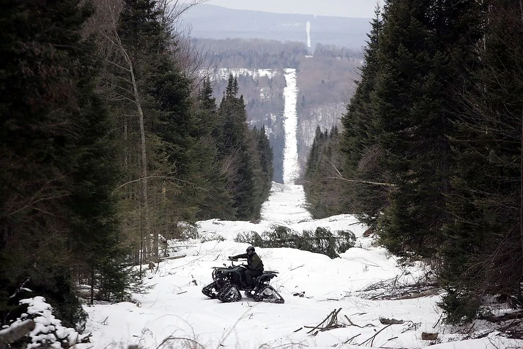 U.S. Border Patrol Agent Andrew Mayer rides a ATV as he looks for signs of illegal entry along the boundary marker cut into the forest marking the line between Canadian territory on the right and the United States near Beecher Falls, Vermont, in a file photo. (Joe Raedle/Getty Images)