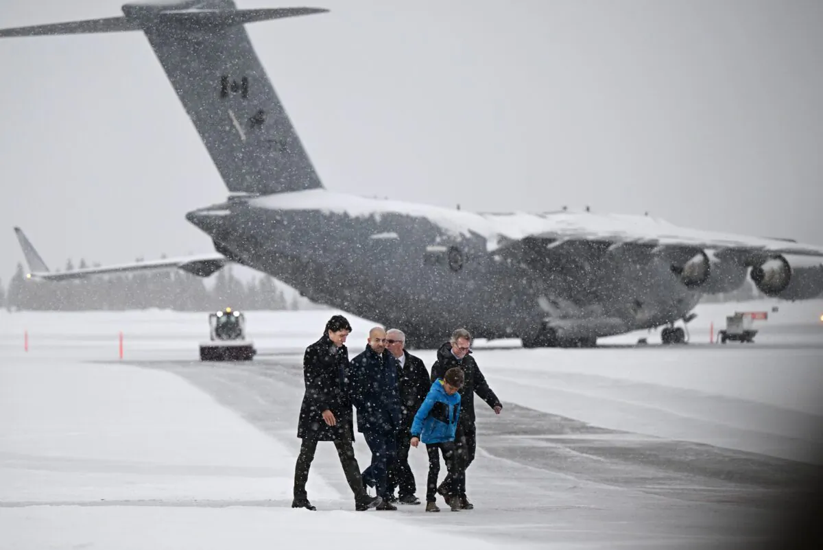(L-R) Prime Minister Justin Trudeau, Yukon Premier Ranj Pillai, a security member, Hadrien Trudeau, and Yukon MP Brendan Hanley arrive at the Erik Nielsen International Airport for a press conference, with an RCAF Boeing C-17 Globemaster in the background, in Whitehorse, Yukon, on Feb. 13, 2023. (Mike Thomas/The Canadian Press)