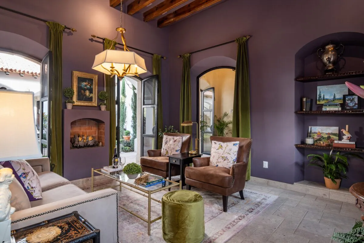 This intimate sitting area that opens onto the adjacent central courtyard features soaring ceilings with exposed beams, a fireplace, and integral bookshelves. (Courtesy of Agave Sotheby's International Realty)
