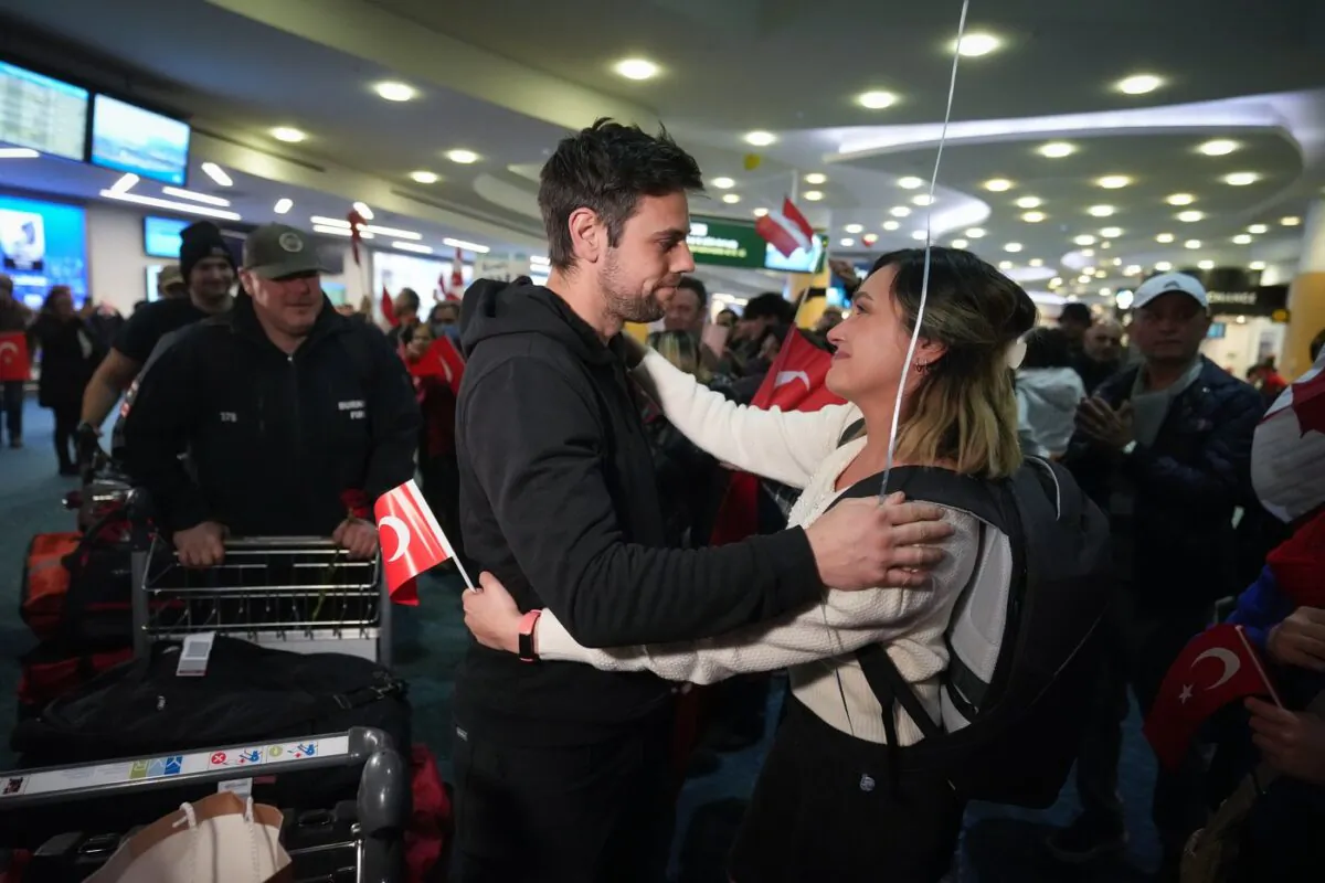 A woman embraces a member of the Burnaby Urban Search and Rescue Team as they are greeted by members of the Turkish Canadian community upon arrival from Turkey at Vancouver International Airport, in Richmond, B.C., on Feb. 14, 2023. (The Canadian Press/Darryl Dyck)