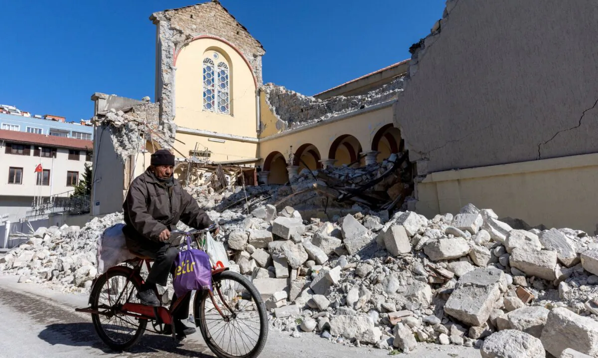 A man rides his bike along a collapsed Roman Catholic church in the aftermath of the deadly earthquake in Iskenderun, a coastal town of Hatay province, Turkey, on Feb. 14, 2023. (Umit Bektas/Reuters)