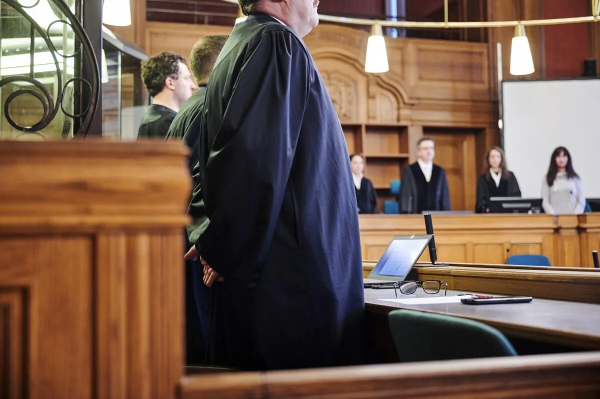 Trial participants stand in room 500 at the Moabit Criminal Court at the opening of the trial against the two men accused of killing their sister in Berlin on Feb. 16, 2023. (Annette Riedl/dpa via AP)