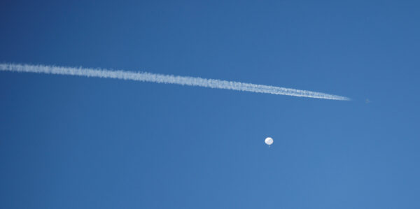 A jet flies by a suspected Chinese spy balloon as it floats off the coast in Surfside Beach