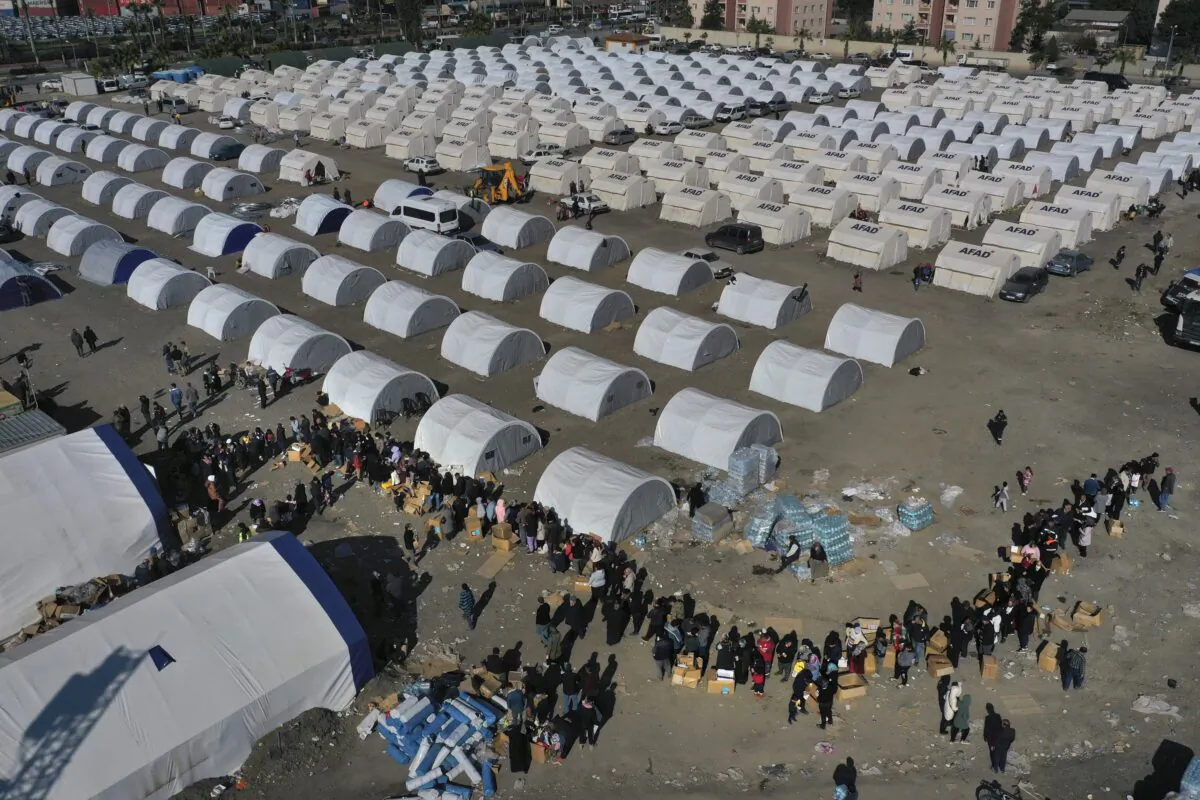 People who lost their houses in the devastating earthquake lineup to receive aid supplies at a makeshift camp in Iskenderun city, southern Turkey, on Feb. 14, 2023. (Hussein Malla/AP Photo)