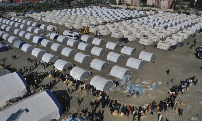People who lost their houses in the devastating earthquake lineup to receive aid supplies at a makeshift camp in Iskenderun city, southern Turkey, on Feb. 14, 2023. (Hussein Malla/AP Photo)