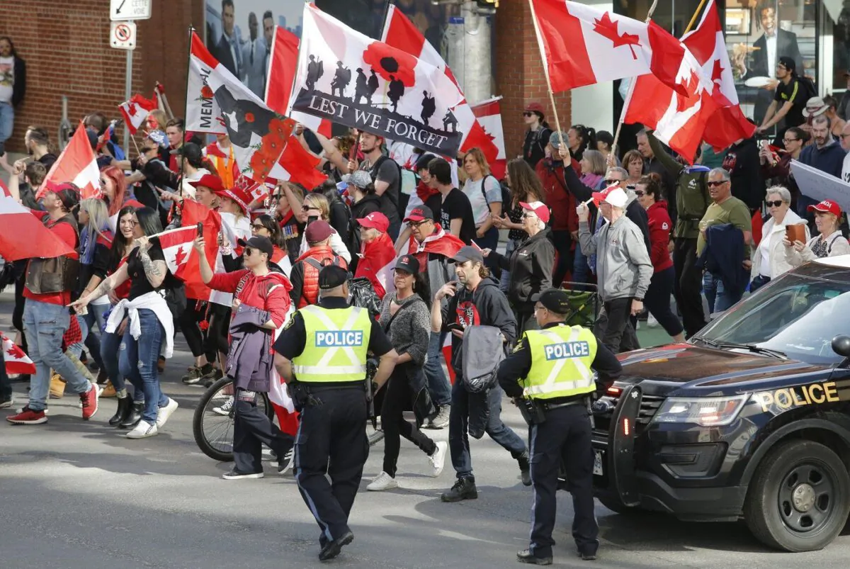 People march past police at a demonstration, part of a convoy-style protest, in Ottawa, on April 30, 2022. (The Canadian Press/ Patrick Doyle)
