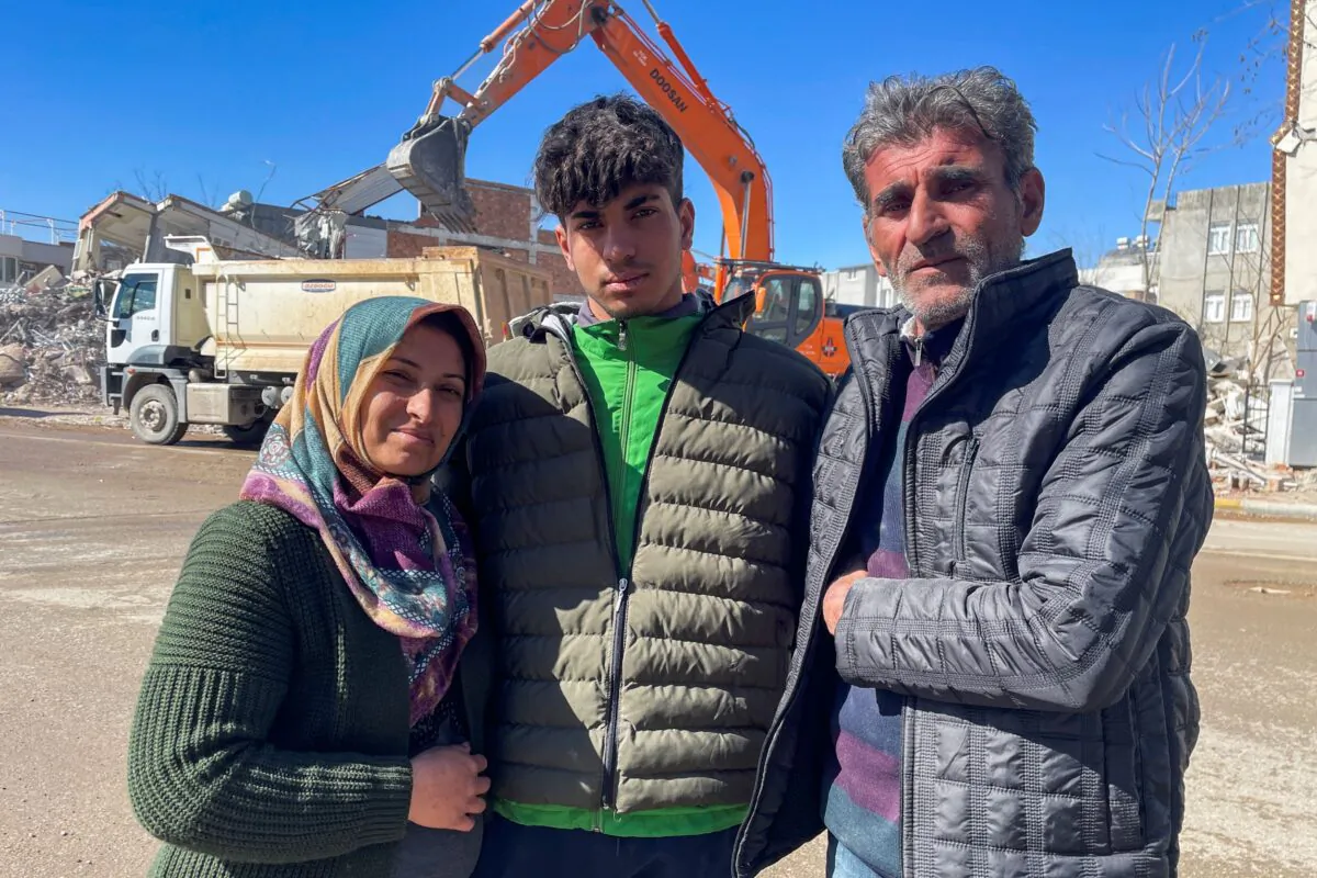 Taha Erdem, 17 (C), his mother Zeliha Erdem (L), and father Ali Erdem pose for a photograph next to the destroyed building where Taha was trapped after the earthquake of Feb. 6, in Adiyaman, Turkey, on Feb. 17, 2023. (Mehmet Mucahit Ceylan/AP Photo)
