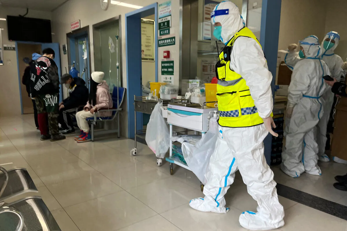 A security worker in a protective suit keeps watch as medical workers attend to patients at the fever department of Tongji Hospital, a major facility for COVID-19 patients, in Wuhan, Hubei Province, China, on Jan. 1, 2023. (Reuters)