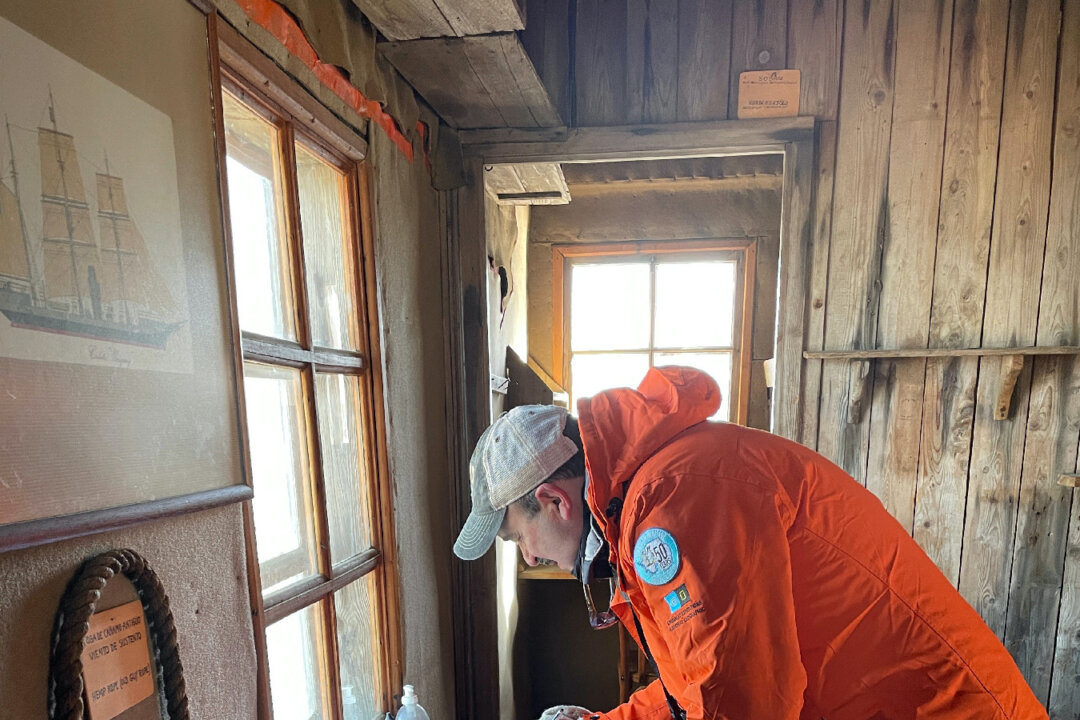 A visitor signs the guest log in tiny Nordenskjold's Hut on Snow Island in Antarctica where six researchers in the Heroic Age of Antarctica Exploration were stuck for 22 months. (Photo courtesy of Lesley Frederikson)