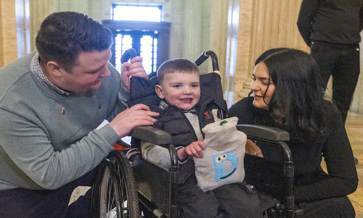 Six-year-old Daithi Mac Gabhann and his parents, father Mairtin Mac Gabhann (left) and mother Seph Ni Mheallain (right), at Parliament Buildings at Stormont on Feb. 14, 2023. The family visited Stormont ahead of a recalled sitting of the Assembly focused on a stalled organ donation law. The law introducing an opt-out donation system in Northern Ireland has been named after Daithi, who is awaiting a heart transplant.(PA Media)