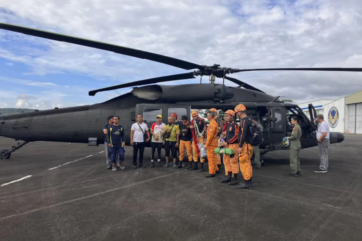 Rescuers stand beside a helicopter as they prepare their search for passengers of a Cessna 340 aircraft with registry number RP-C2080 at Camalig town, Albay province, southeast of Manila, Philippines, on Feb. 21, 2023. (Civil Aviation Authority of the Philippines via AP)