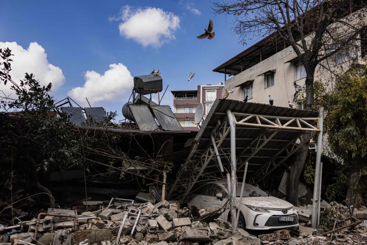 A pigeon flies over a damaged car after a 6.4-magnitude quake hit the Hatay Province in Antakya, southern Turkey, on Feb. 21, 2023. (Sameer Al-Doumy/AFP via Getty Images)