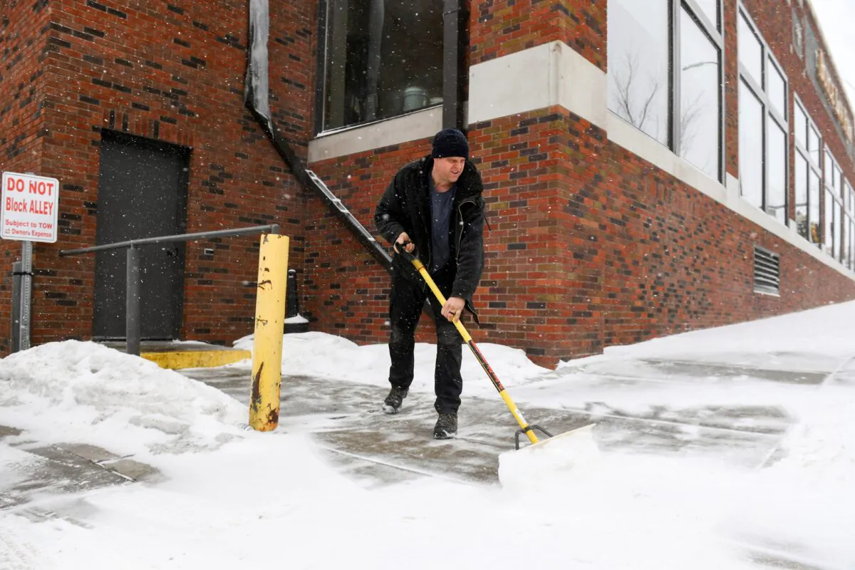David Smith shovels the sidewalk as the first snow falls ahead of a winter storm in Sioux Falls, S.D., on Feb. 21, 2023. (Erin Woodiel/The Argus Leader via AP)