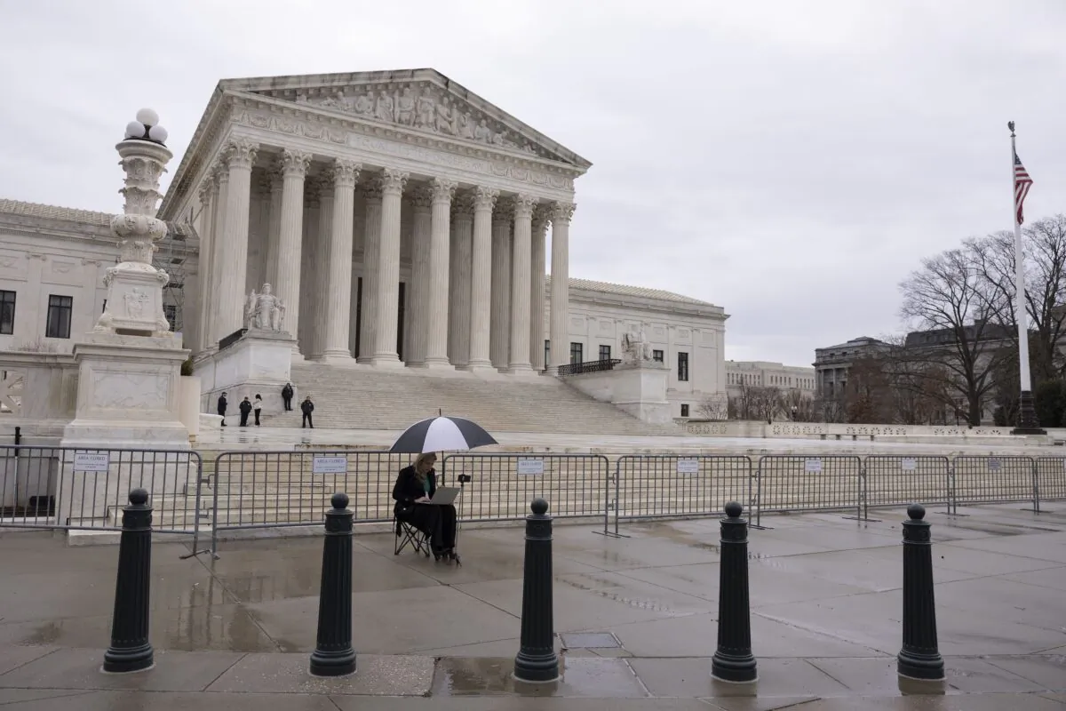 A woman works on her laptop outside the U.S. Supreme Court in Washington on Feb. 22, 2023. (Anna Moneymaker/Getty Images)