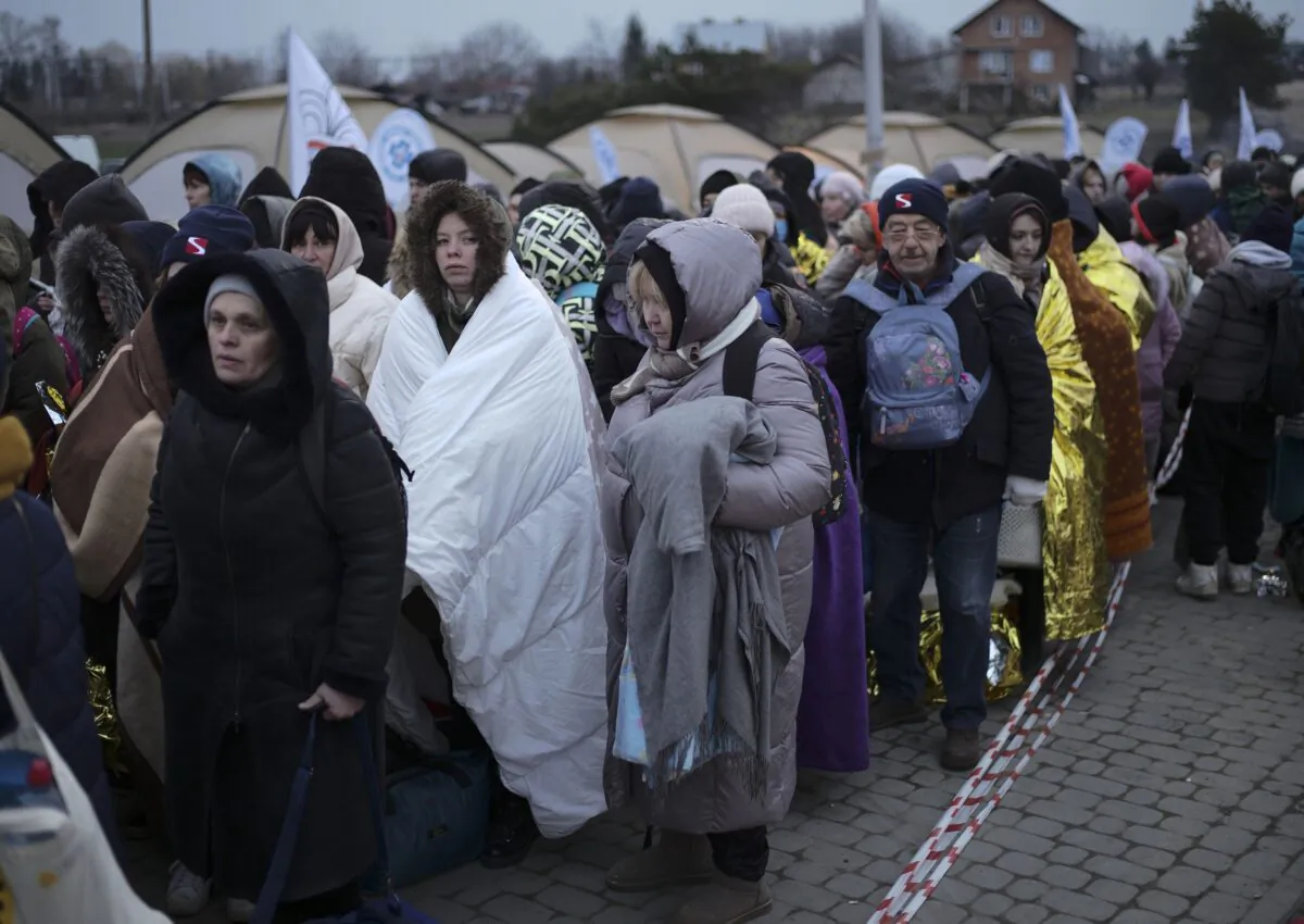 Refugees wait in a crowd for transportation after fleeing from the Ukraine and arriving at the border crossing in Medyka, Poland, on March 7, 2022. (Markus Schreiber/AP Photo)