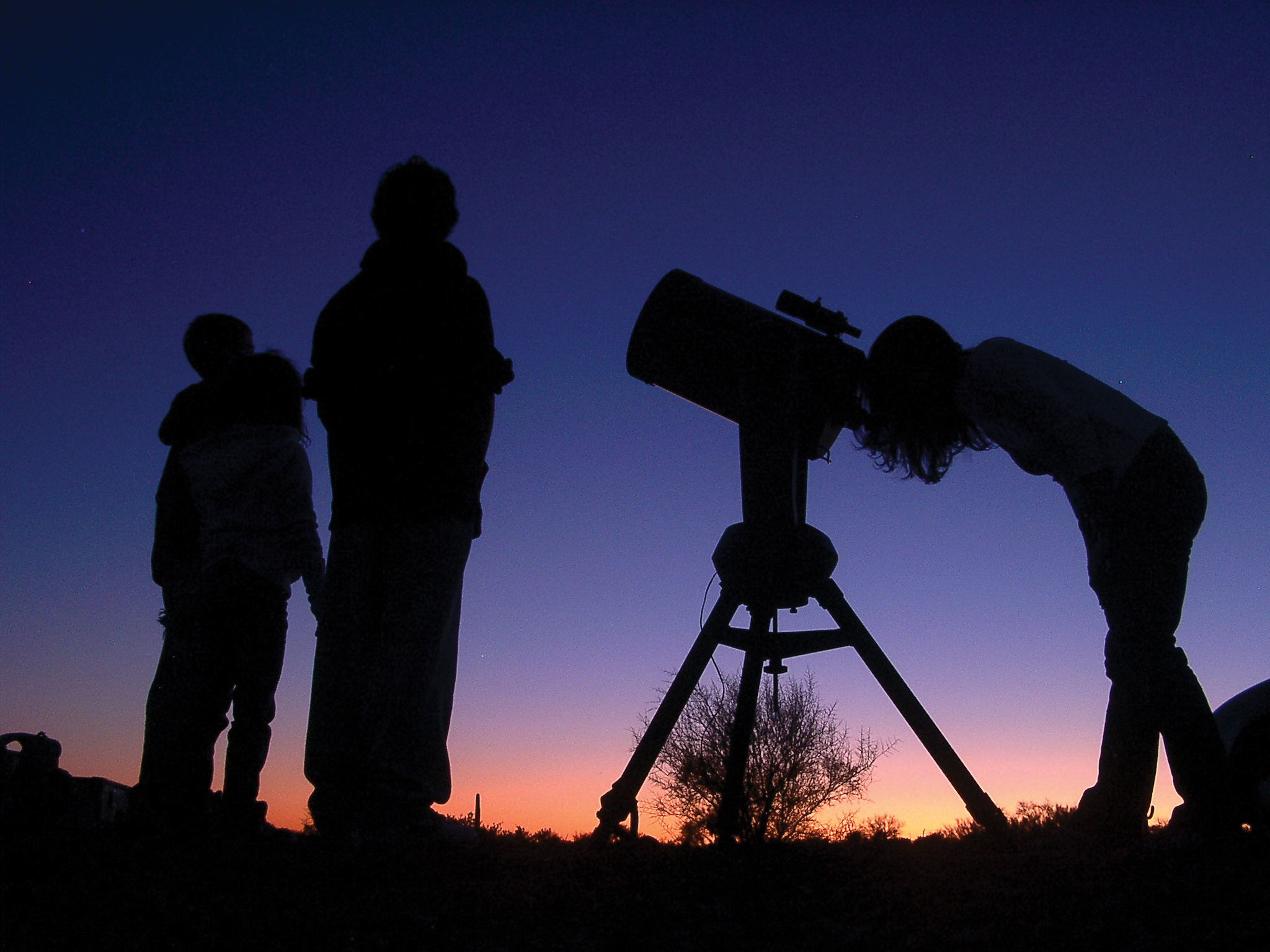 silhouettes of a telescope and people